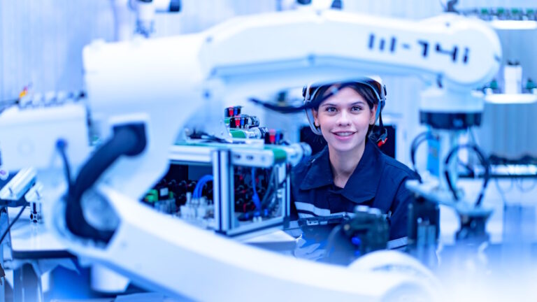Ragazza laureata in ingegneria programma un braccio robot in una fabrica