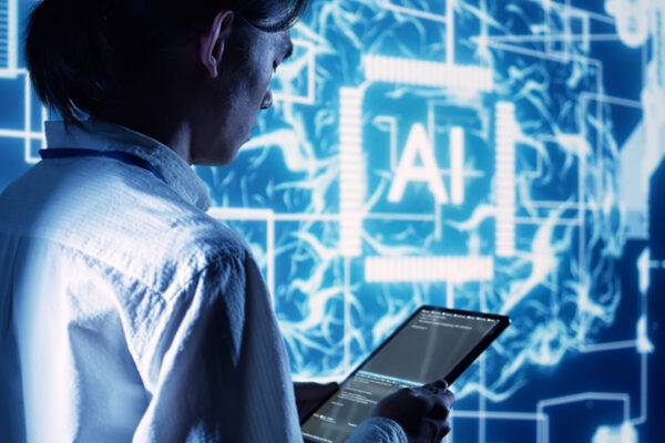 Incontro tra l’Agenzia per la cybersicurezza nazionale e le università italiane Immagine di repertorio, tecnico osserva un tablet, sullo sfondo un grande schermo con il logo AI