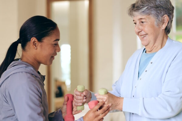 L’assistenza domiciliare migliora la salute mentale e riduce i costi sanitari Operatrice sanitaria aiuta anziana signora con gli esercizi di riabilitazione motoria