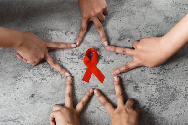 Nuove prospettive per i pazienti Hiv grazie allo studio congiunto mani formano una stella a cinque punte intorno al nastrino rosso simbolo della lotta all'HIV