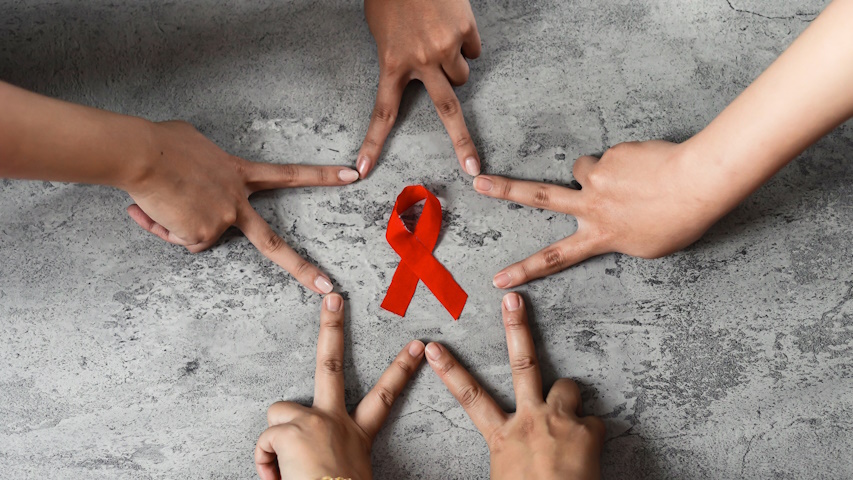 mani formano una stella a cinque punte intorno al nastrino rosso simbolo della lotta all'HIV